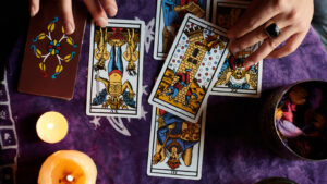 Close-up of a fortune teller reading tarot cards on a table with purple tablecloth