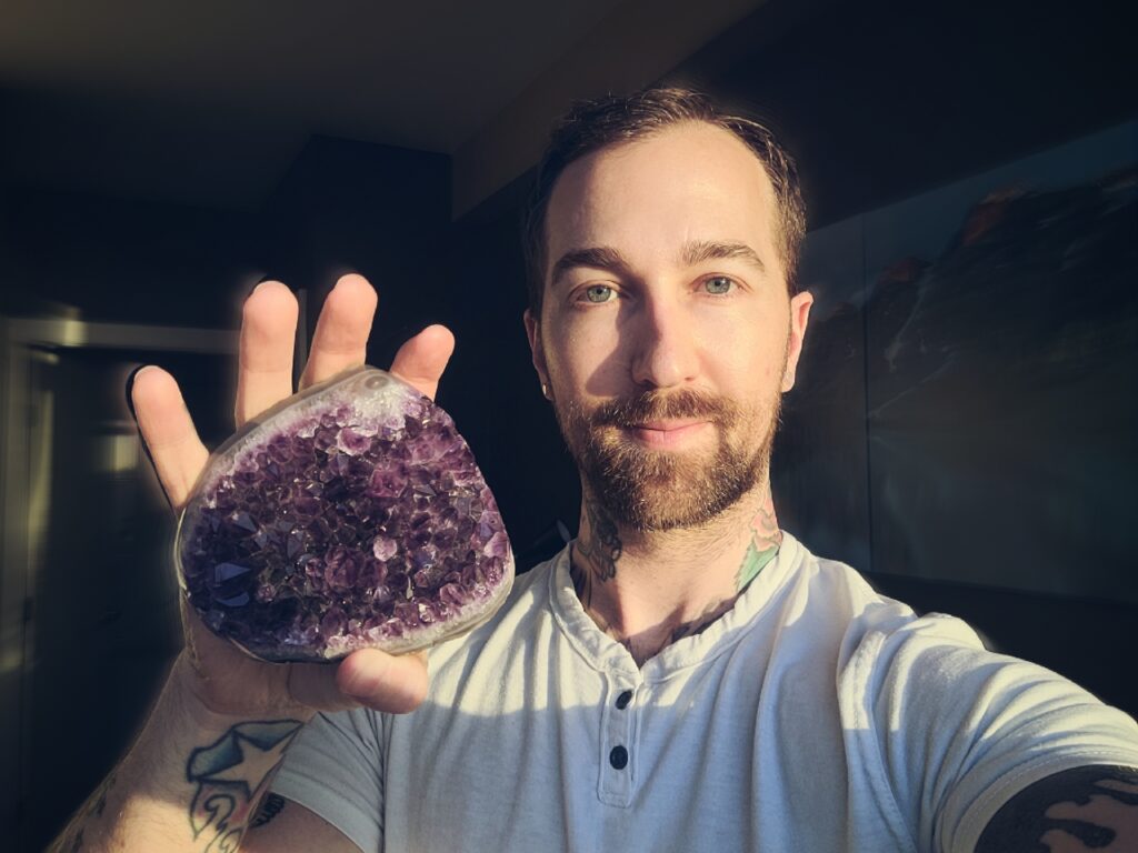 Chris-Bennett-Psychic-Tarot-Reader-holding-a-large-cluster-of-Amethsyt-for-psychic-protection