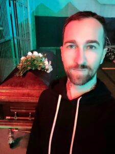 The-worlds-best-tarot-reader-Chris-Bennett-based-out-of-Vancouver-Canada in front of a coffin at night on the set of School Spirits
