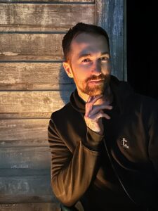 The worlds best tarot reader Chris Bennett based out of Vancouver Canada. Male in black hoodie at night with candle glow on face