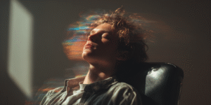 Person reclined with eyes closed, surrounded by swirling ink-like currents representing intuitive surrender and the quieting of mental noise.